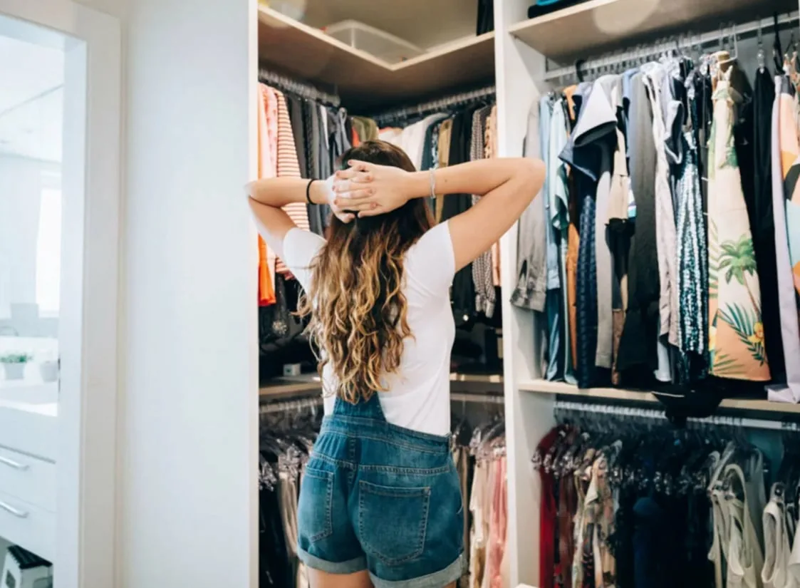 クローゼットの前で頭に手を当てて服を眺める女性