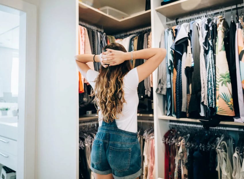 クローゼットの前で頭に手を当てて服を眺める女性